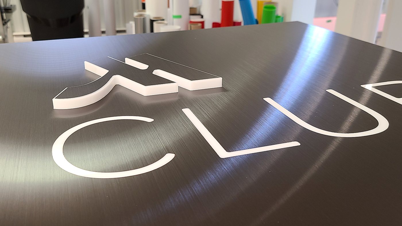 Illuminated acrylic letters on brushed aluminum panel